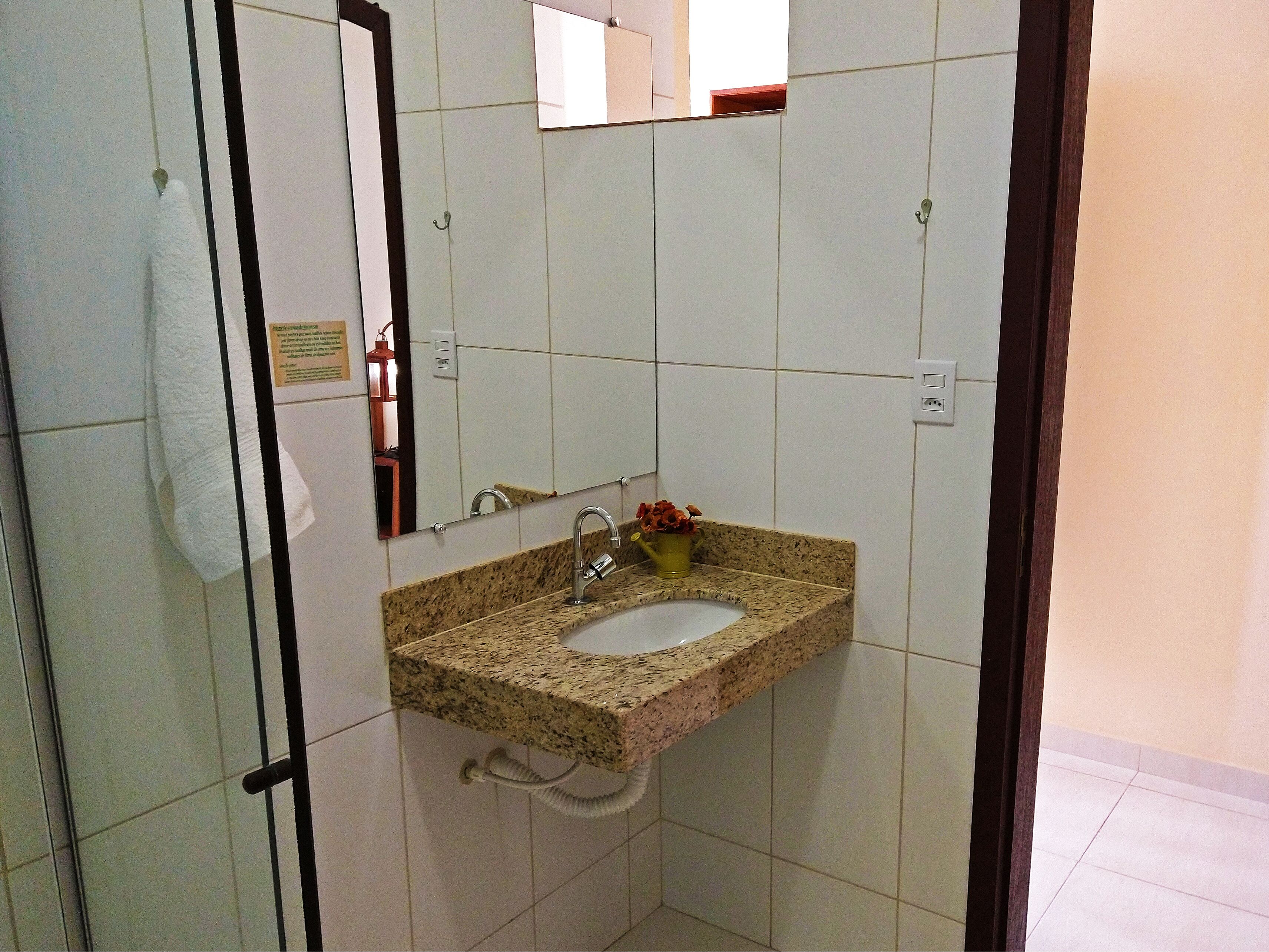A bathroom with a granite countertop sink, a mirror, and a towel hanging on a rack.