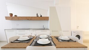 A modern kitchen with white cabinetry, a wooden countertop, and a built-in washing machine.