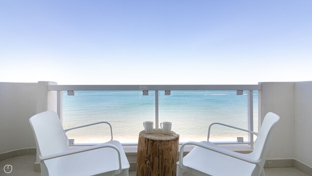 A balcony with two white chairs and a small wooden table, overlooking a beach with clear blue water. - Rivazzurra Homes - 36 (Termoli)