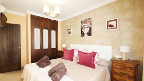 Ein Hotelzimmer mit einem großen Bett, einem Holzschrank und einem Nachttisch mit Lampe.
