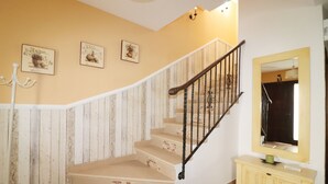 Eine Treppe mit Holzgeländer, beigen Stufen und einer hellen Wand mit drei gerahmten Bildern.