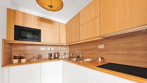 A modern kitchen with wooden cabinets, a microwave, a sink, and various kitchen appliances. - Spacious Old Town Square Apartment (Hlavní mesto Praha)