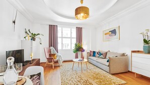 A modern living room with a sofa, a coffee table, a chair, and a TV. - Spacious Old Town Square Apartment (Hlavní mesto Praha)