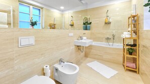 A modern bathroom with a bidet, sink, and bathtub. - Spacious Old Town Square Apartment (Hlavní mesto Praha)