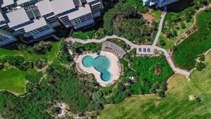 An aerial view of a property with a swimming pool, landscaped gardens, and modern buildings.