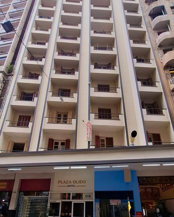 Ein mehrstöckiges Hotel mit Balkonen an jeder Etage, ein Schild mit der Aufschrift 'Plaza Olido Hotel' und ein Laden im Erdgeschoss.