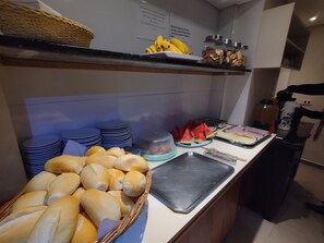 Ein reichhaltiges Buffet mit Brot, Bananen, Wassermelone und verschiedenen Beilagen.