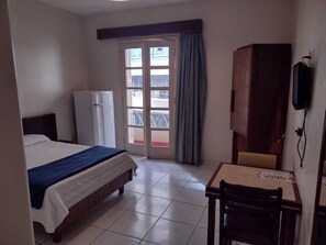 Ein Hotelzimmer mit Bett, Schreibtisch mit Stuhl, Kleiderschrank, Fernseher und Fenster mit Aussicht.