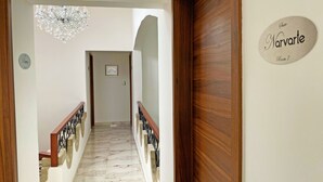 A hotel hallway with a marble floor, wooden doors, and a chandelier.