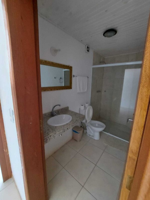 A bathroom with a sink, mirror, toilet, and shower. - Pousada do Mica (Imbituba)