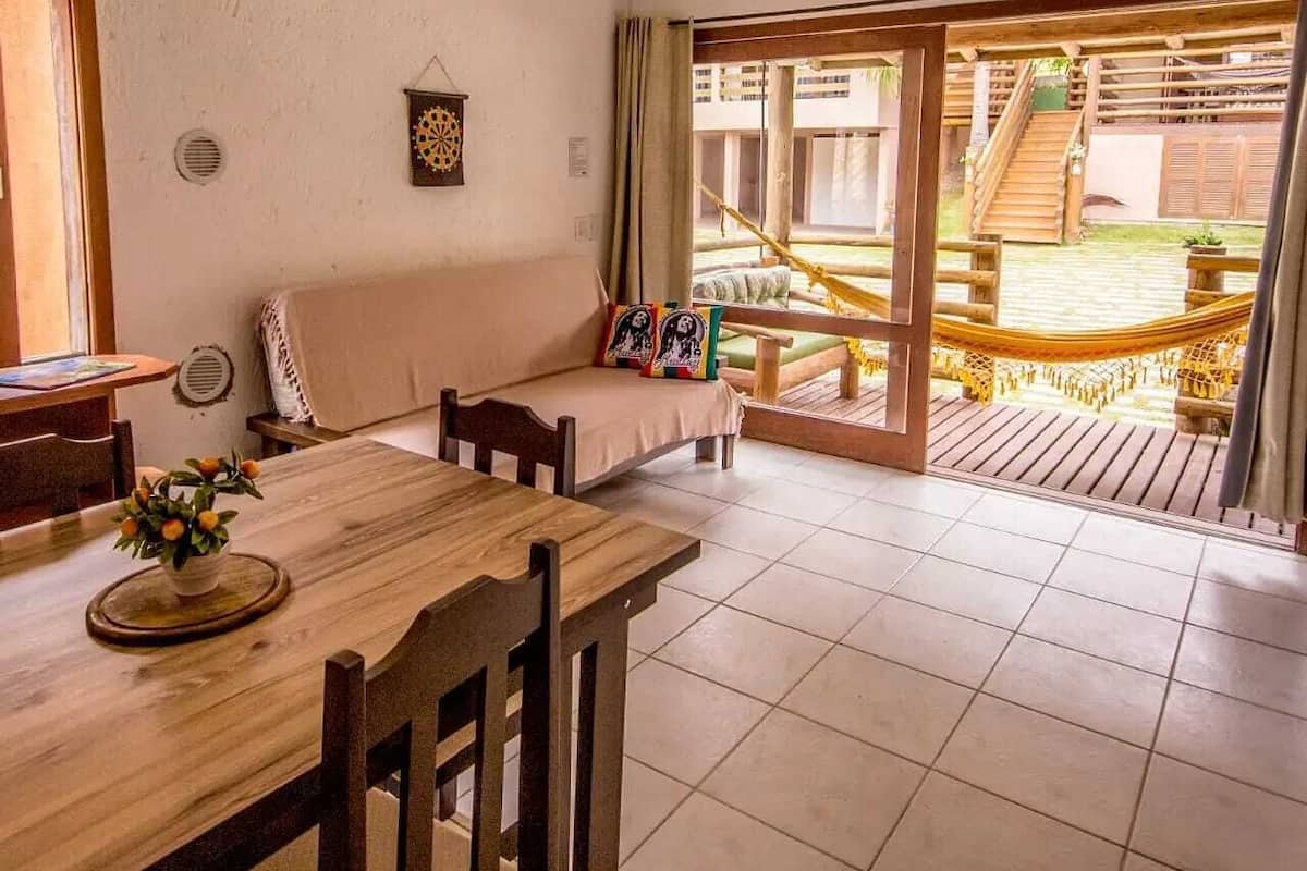 Ein gemütlicher Raum mit einem Holzesstisch, einer gepolsterten Bank und Blick auf eine Holzterrasse und eine Treppe.