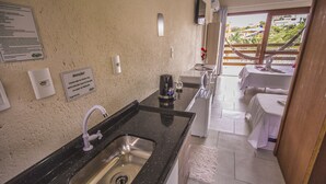 A kitchen with a sink, a coffee machine, and a sign on the wall. - Pousada do Mica (Imbituba)