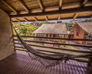 A hammock on a wooden deck with a view of traditional buildings and a clear sky. - Pousada do Mica (Imbituba)