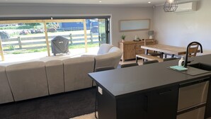 Una cocina moderna con una isla central, un comedor con banco y una sala de estar con sofá.