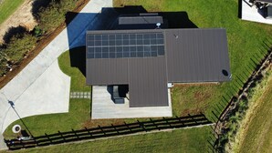 Vista aérea de un edificio moderno con techo plano, paneles solares y patio cercado.