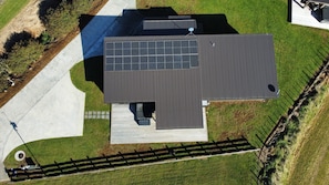 Vue aérienne d’un bâtiment moderne doté d’un toit plat, de panneaux solaires et d’une allée pavée.