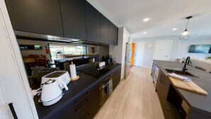 Una cocina moderna con armarios oscuros, encimera negra y comedor de madera.