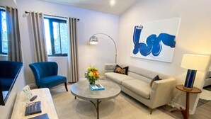 A modern living room with a sofa, two armchairs, a coffee table, and a lamp.