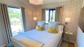 A modern bedroom with a large bed, two bedside lamps, and a view of the outdoors.