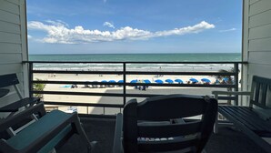A balcony with a view of the beach, featuring sun loungers and umbrellas.