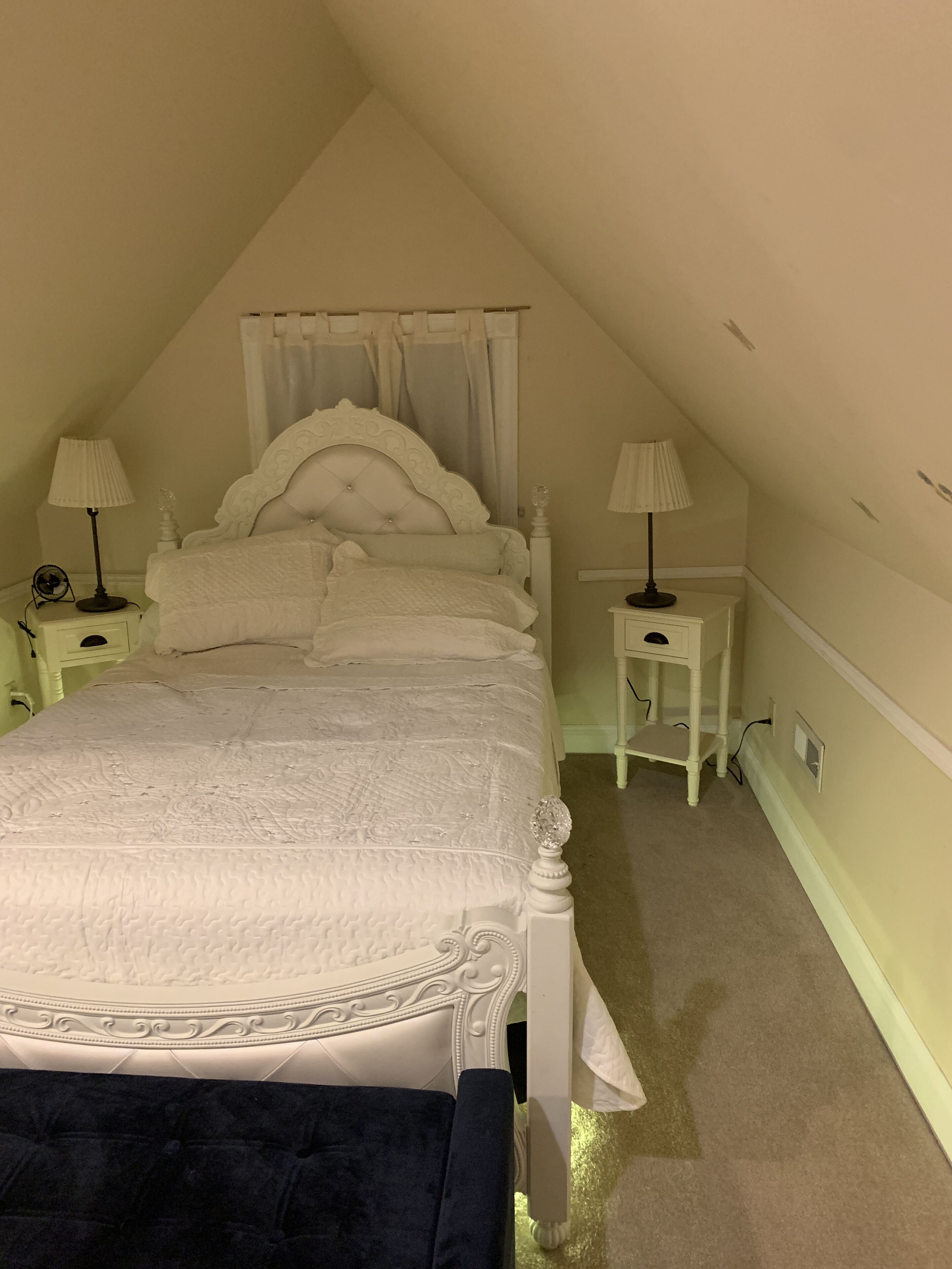 Ein Schlafzimmer mit einem großen Bett, zwei Nachttischen mit Lampen, einem Beistelltisch und einem Teppichboden.