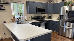 Una cocina moderna con gabinetes grises, electrodomésticos de acero inoxidable y una isla grande.