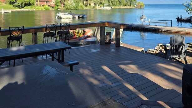 Terraza junto al lago con asientos exteriores, vista al lago y una cadena montañosa distante.