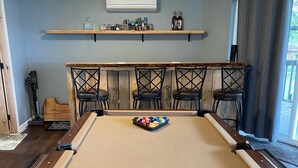 Una mesa de billar con una bola en el centro, rodeada de cuatro sillas.