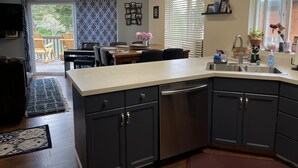 Una cocina moderna con armarios oscuros, una isla central y una zona de comedor con un piano.