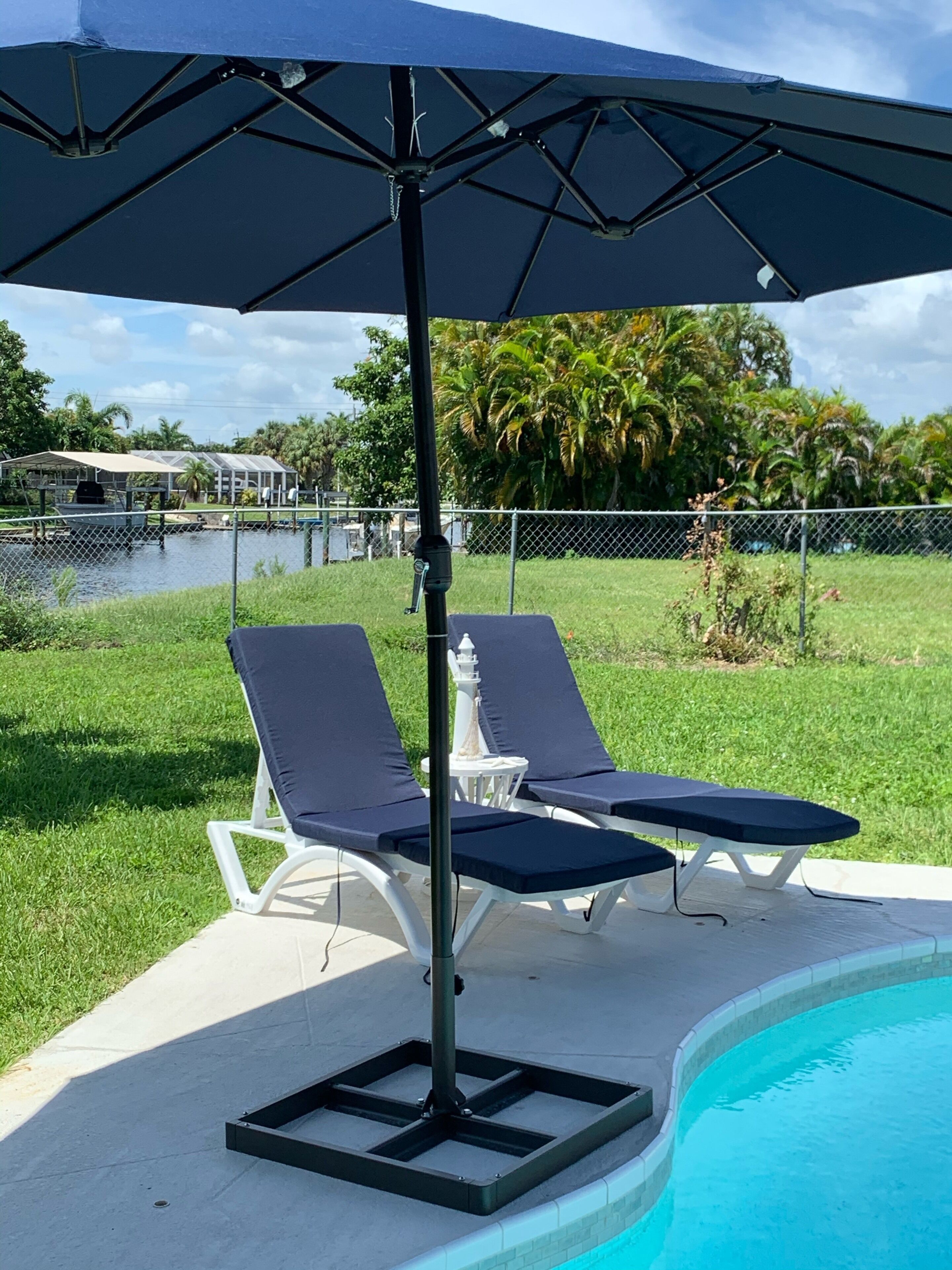 A poolside area with two lounge chairs and a large umbrella.