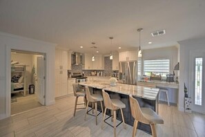 A modern kitchen with a large island, bar stools, and pendant lighting.