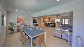 A spacious living area with a dining table and chairs, a sofa, and a kitchen in the background. - Canelas Home, you’re Home away from Home (Cape Coral)