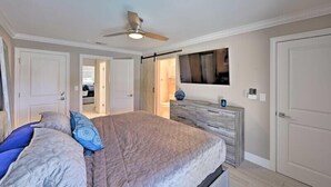 A bedroom with a bed, a dresser, a ceiling fan, and a TV on the wall. - Canelas Home, you’re Home away from Home (Cape Coral)
