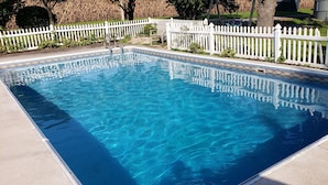 Une piscine rectangulaire entourée d’une clôture en bois peinte en blanc.