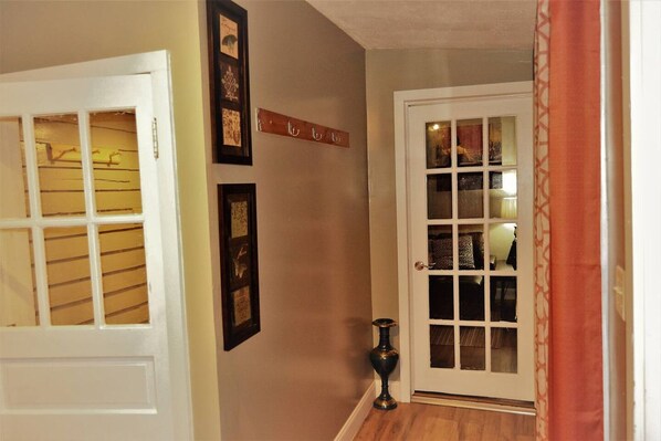 A hallway with a white door, a glass door with shelves, and a small table.