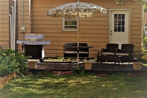 A backyard with a grill, outdoor furniture, and a door.