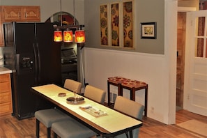 A kitchen with a black refrigerator, a dining table with chairs, and a small wooden side table.