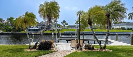 A waterfront property with a dock, palm trees, and a grassy area.