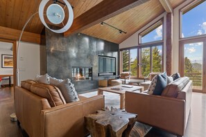 Relax in this spacious living room with a fireplace, leather sofas, and a large stone accent wall.