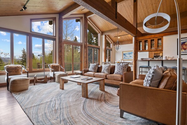 Relax in this spacious living area with expansive views of the surrounding landscape, a cozy seating arrangement, and a wooden coffee table.