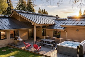 Una cabaña de madera con terraza, mobiliario exterior y un jacuzzi.