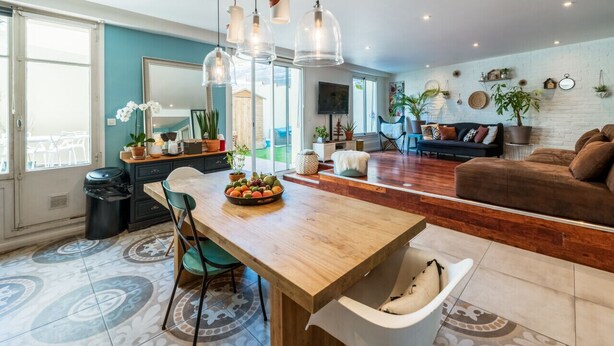 A modern kitchen with a wooden island, pendant lights, and a bowl of fruit. - Appartement Charles - Welkeys (Marseille)