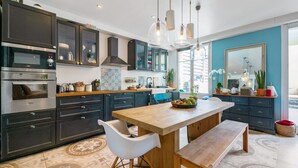 A modern kitchen with dark cabinets, a wooden island, and a large window. - Appartement Charles - Welkeys (Marseille)