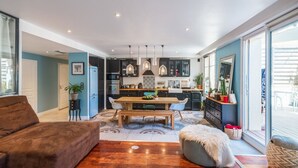 A modern living room with a sofa, a dining table, and a kitchen in the background. - Appartement Charles - Welkeys (Marseille)