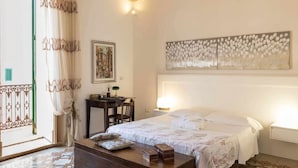 Quarto com cama, mesa de cabeceira, luminária, obra de arte e vista para o exterior.