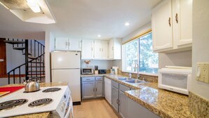 A modern kitchen with white cabinets, granite countertops, a built-in oven, and a stainless steel stove.