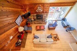 A cozy cabin interior with a stone fireplace, wooden walls, a sofa set, and a television. - Beautiful Mountain Townhome, Modern Amenities 472 (Mammoth Lakes)