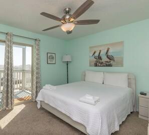 A clean, well-lit bedroom with a bed, a ceiling fan, a painting, and a balcony view. - Beachside Escape | Heated Pool, Hot Tub & Ocean Views (Corpus Christi)