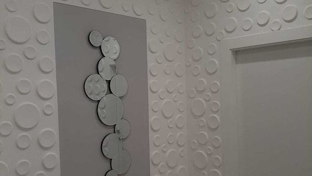 A room with a textured wall featuring circular patterns and a central decorative panel with circular mirrors. - NEW LUXURY BIG APARTMENT (Pescara)