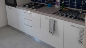 A modern kitchen with white cabinets, a gas stove, a built-in oven, and a blue-tiled backsplash. - NEW LUXURY BIG APARTMENT (Pescara)